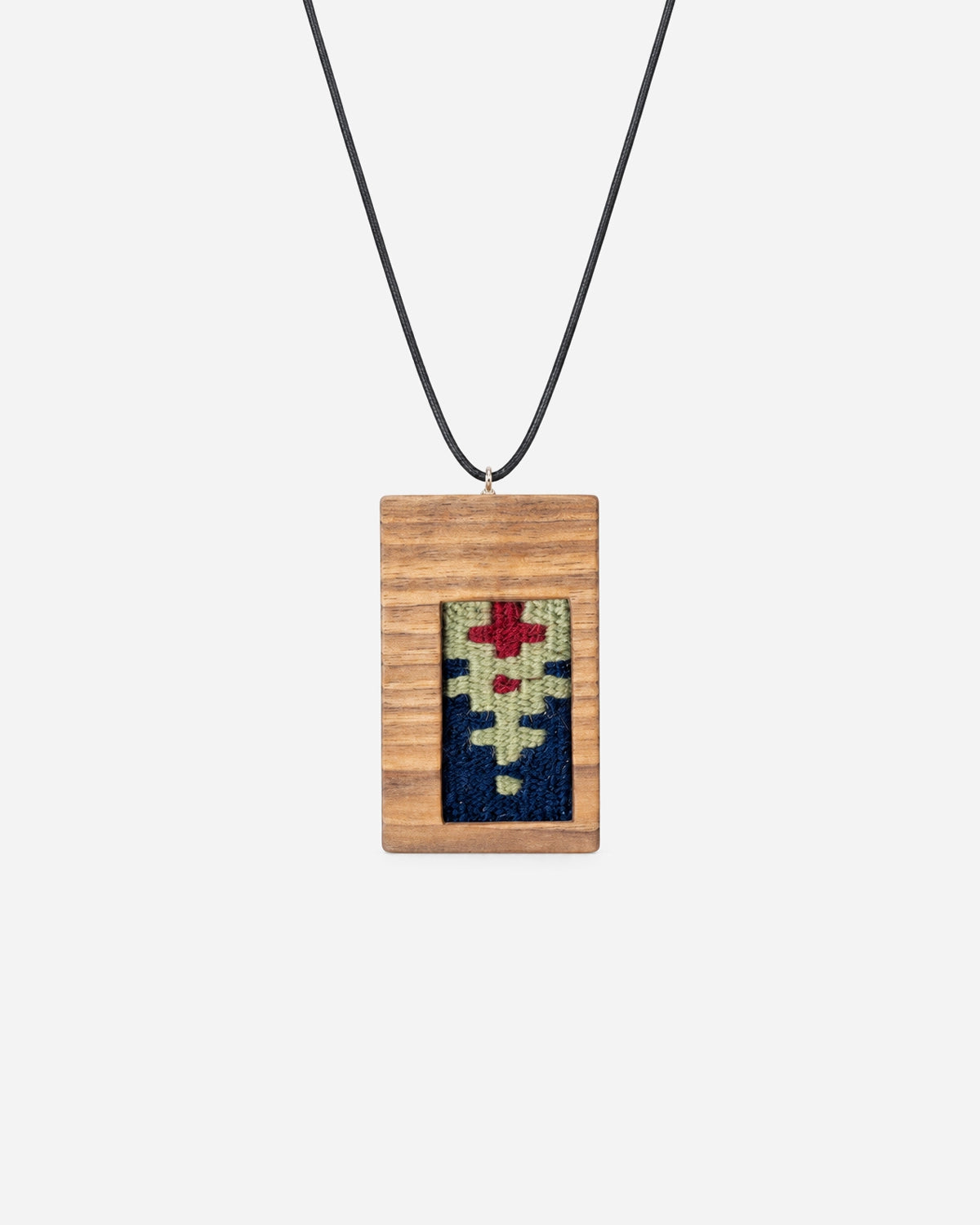 Ruby Frame Kilim Necklace with ruby-red, sage and navy weaving in a rectangular walnut frame on a black cord.