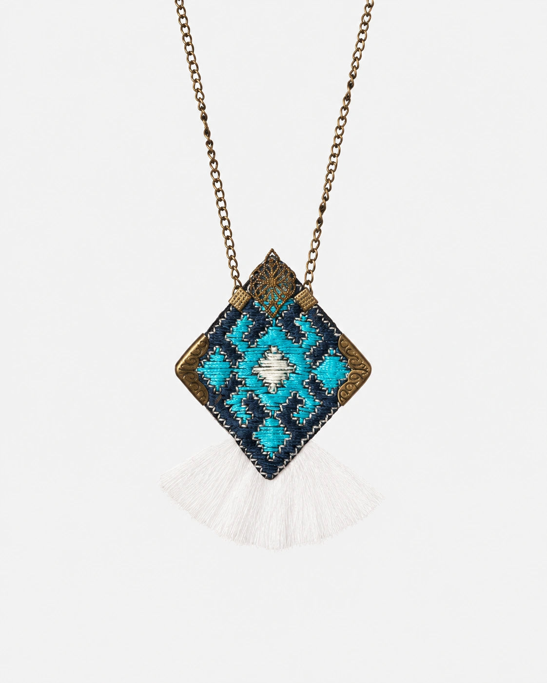 Turquoise Tradition diamond pendant with turquoise and dark woven patterns, gold-tone details and white fringe.